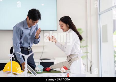 Collaboration and Engineering. Two engineers discussing sustainable construction innovations with scale models. Stock Photo