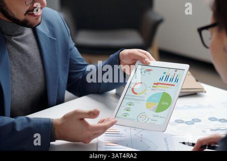 Man Holding Tablet Presenting Data During Meeting Stock Photo