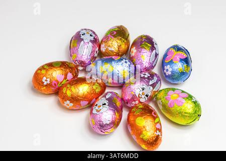 Multicolored chocolate Easter eggs in wrappers with bunnies and flowers. Stock Photo