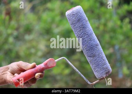 Used paint roller machine used to paint flat surfaces like walls held on the hand on outdoors Stock Photo