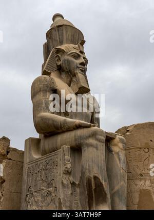 A monumental ancient Egyptian statue of a seated pharaoh at the ...