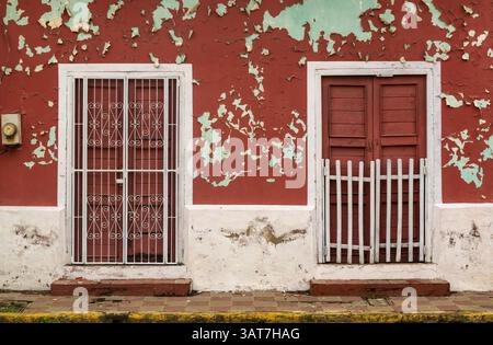 Peeling burgundy red painted wall of a house in Leon, Nicaragua. Stock Photo