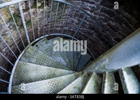 Steps of old metal spiral staircase disappear in darkness Stock Photo