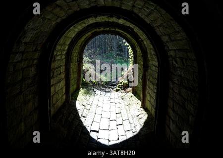 Dark tunnel emerges into bright sunlight beneath the Longdendale Trail, Hadfield, High Peak, Derbyshire. Stock Photo