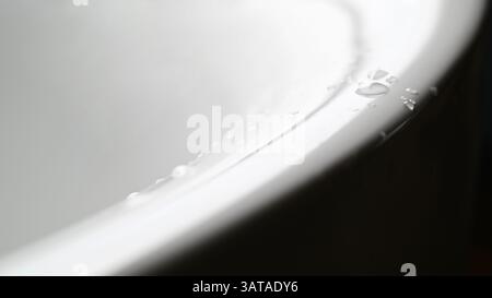 A bathtub with water splashes and drops on the edge of the tub as a background Stock Photo