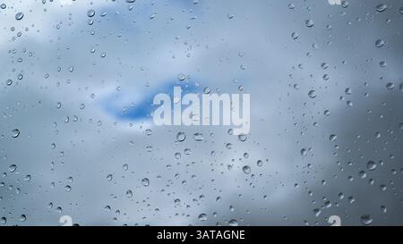 Raindrops on a window with clouds on the background Stock Photo