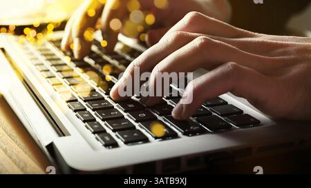 Businessman - texting - typing remote online on notebook - man hands on keyboard, golden sunshine bokeh bubble falls over the keyboard. Stock Photo