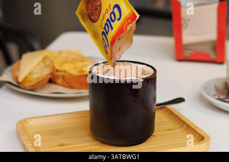 Preparing a Comforting Breakfast, Pouring Cola Cao into Hot Milk Stock Photo