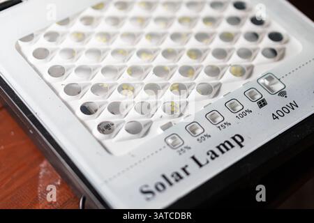 A close-up view of a solar lamp with a grid of LED lights, featuring control buttons for brightness settings and a power rating of 400S. Stock Photo