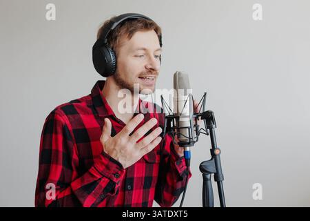 Young podcast creator streaming audio broadcast or recording audiobook. Broadcasting an interview using microphone Stock Photo