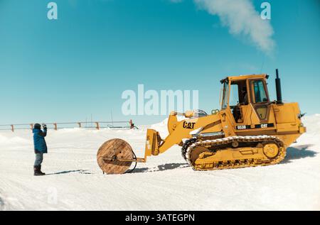 Two technicians prepare to lay a large-section electrical cable with a coil weighing several tonnes. Concordia Antarctic Research Station, Dome C plat Stock Photo