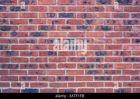 Background from a red brick wall with burnt black spots Stock Photo