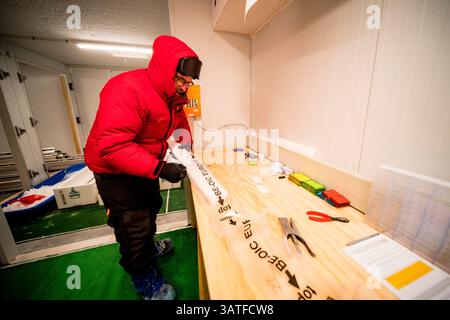 Two scientists cut and pack ice cores. Here, half a core is wrapped in a plastic container. Concordia Antarctic Research Station, Dome C plateau, East Stock Photo