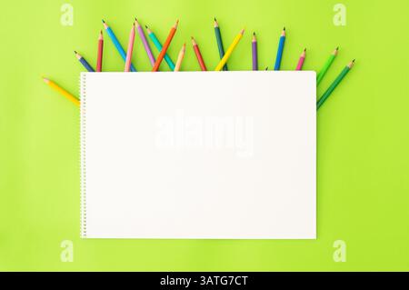 Crayons with drawing book, colorful dry painting pencils on green background, back to school art design Stock Photo