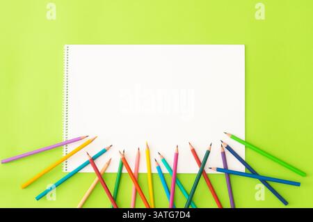 Crayons with drawing book, colorful dry painting pencils on green background, back to school art design Stock Photo