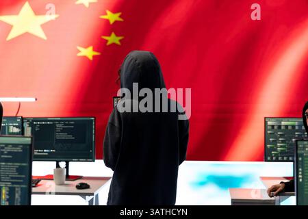 Governmental hacker in high tech office with Chinese flag shown on big screen, IT expert engaged in cyber espionage and criminal activity. Spreading fake news and brainwashing the nation. Stock Photo