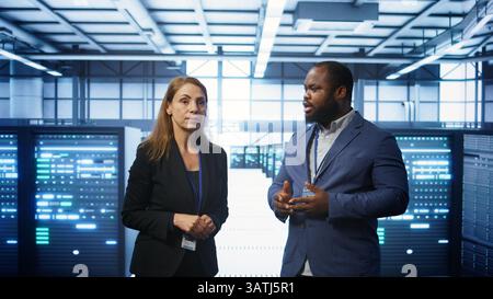 Team of admins in high tech data center looking at hologram visualization. Engineer and coworker working on securing serves using AR tech, preventing hacker attacks, camera B Stock Photo