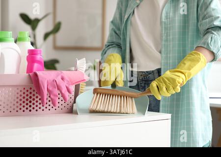 Woman with cleaning supplies and dustpan brushing dust from table in modern office, closeup Stock Photo