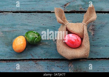 An Easter nest made from a jute sack with ears and colorful Easter eggs on a wooden base Stock Photo