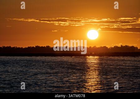 Vivid sunset over the Lucio del Lobo wetland creates stunning reflections in the water, showcasing the beauty of Doñana in Andalusia. Stock Photo