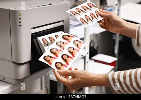 Worker with passport photos of women near modern printer indoors, closeup Stock Photo