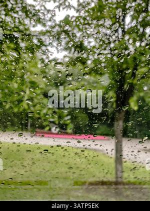 Raindrops on window with blurred green trees background Stock Photo