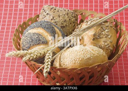 Bread rolls in a basket with ears of wheat on a red background Stock Photo