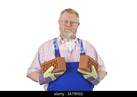 Bricklayer in blue dungarees holds bricks in his hand Stock Photo