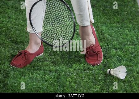 Woman's legs, badminton racket and shuttlecock on a green grass Stock Photo