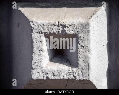 Close-up of a weathered stone wall with a square recess and visible cracks. Stock Photo