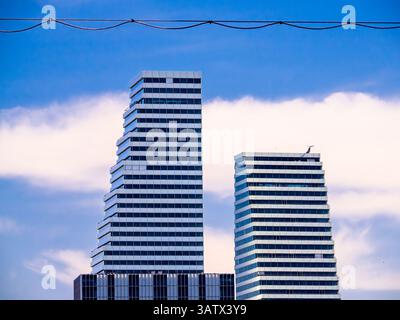 Basel, Switzerland - April 2, 2025: Two modern Roche skyscrapers in Basel with a unique stepped design against a blue sky with clouds. Stock Photo