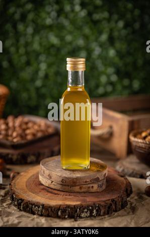 Macadamia nut oil in a glass bottle sits on rustic wooden coasters Stock Photo