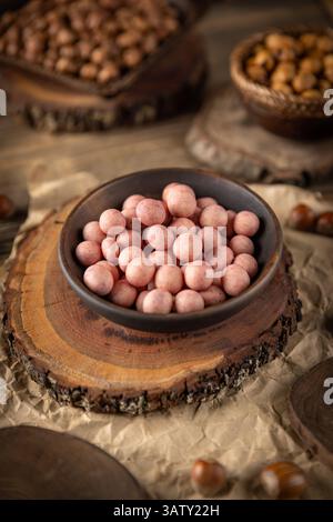 Bowl of covered hazelnuts on wooden serving board with other nuts in background Stock Photo
