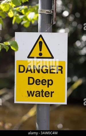 Danger Deep Water sign on metal post in front of UK open water. Stock Photo