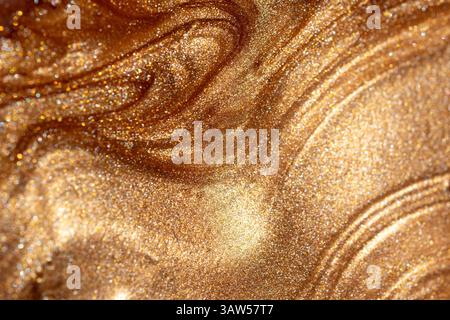 Texture background with golden shimmering cosmetic body spray or gel. Glowing backdrop. Stock Photo
