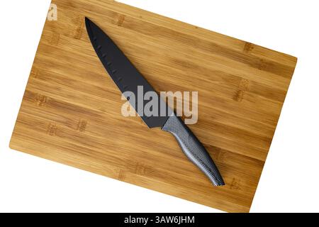 Black Knife on Bamboo Cutting Board:A sleek, black chef's knife rests on a light brown bamboo cutting board, ready for culinary creation.  The image o Stock Photo