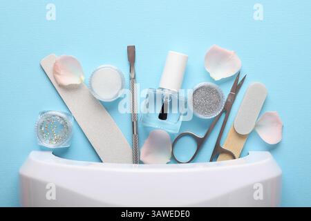 Set of different manicure tools and UV lamp on light blue background, flat lay Stock Photo