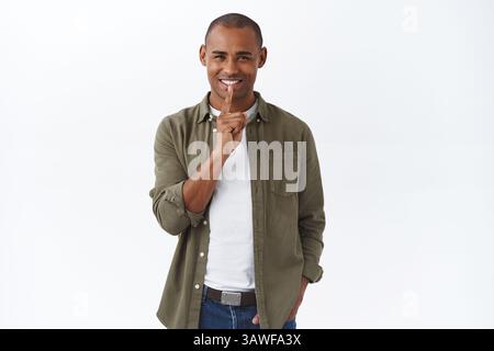 Tricky young charismatic african-american handsome man prepare surpirse, shushing with devious happy smile, squinting having secret, tell be quiet, st Stock Photo