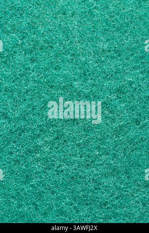 close-up macro view of textured bright green rough fibrous surface of cleaning sponge, small dense interwoven strands background, abstract wallpaper Stock Photo