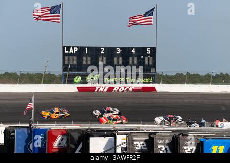 Four race cars pass through curve in front of grandstand filled with ...