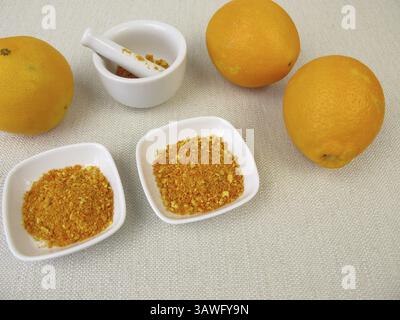 Finely grind orange zest from organic oranges in a mortar Stock Photo