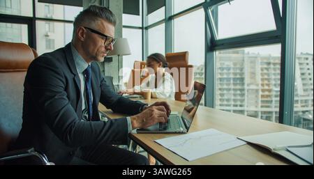 Businesspeople working on laptops in office Stock Photo