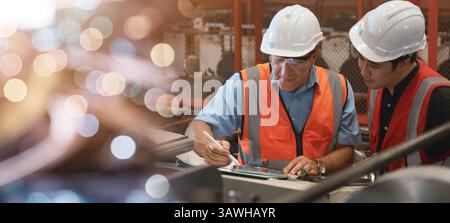 Engineer teaching apprentice to use metal sheet stamping machine Stock Photo