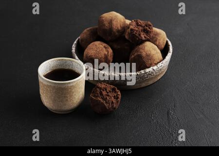Homemade truffles with cup of coffee on the black background. 2 May Truffles day Stock Photo