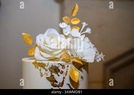 Closeup of a wedding cake with gold leaf and sugar flowers Stock Photo
