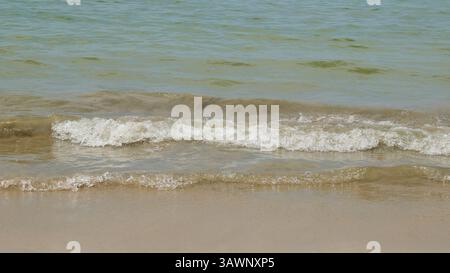 close-up of calm sea waves rolling towards the shore, ripples or gentle swells approach sand, travel, nature and relaxation concept, soft focus Stock Photo