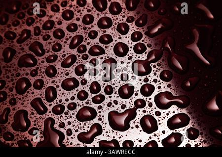 Water droplets on a red surface with light and shadow on the surface. Stock Photo