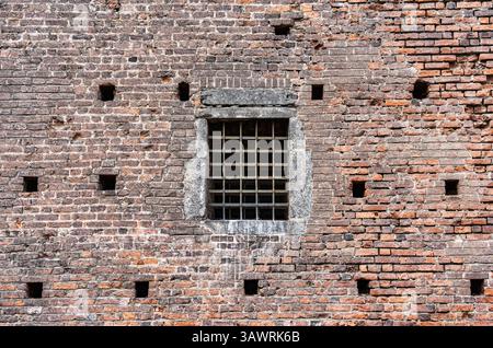 A close-up view of a window on a medieval brick wall, protected by a heavy iron grate part of the historic Sforza Castle (Castello Sforzesco) in Milan Stock Photo