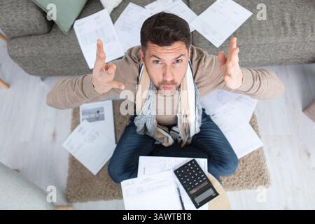 frustrated man at home calculating bill payments Stock Photo