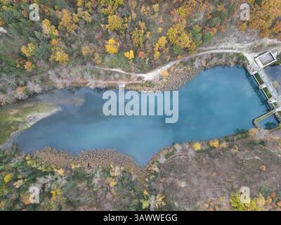 Aerial photo of Lago di Casette dam with colorful autumn foliage, taken in Marche, Italy with DJI Mini 3 Pro drone. Clear water and forest detail. Stock Photo